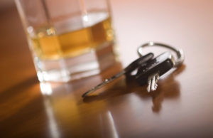 Car keys next to a glass of alcohol.