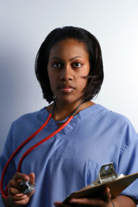 A female in scrubs is holding a stethoscope and a clipboard.