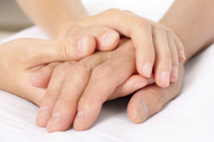 Two small hands gently holding a larger hand.