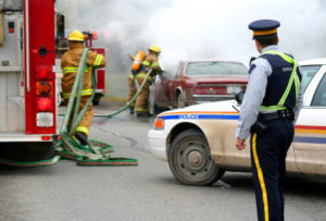 Firemen are putting out a car on fire on the freeway.