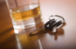 Car keys next to a glass of alcohol.