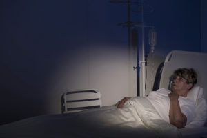 A woman is laying in a hospital bed in a dark room.