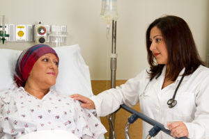 A doctor touching the shoulder of a patient in a hospital bed.