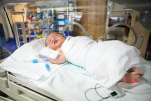 A baby in a hospital bed connected to monitors.