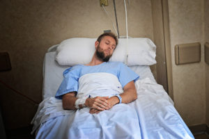 A young man is sleeping in a hospital bed.