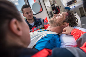 Paramedics looking over an unconscious man with head wounds.