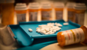 Prescription pills and pill bottles on a teal surface.