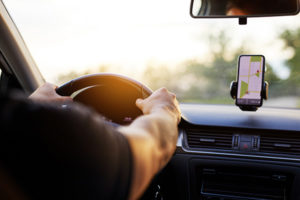 A man driving while the phone is clipped up to show navigation.