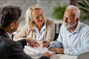 An older couple is talking to a lawyer while he points to a contract.
