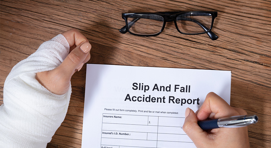 Someone with their arm wrapped is filling out a slip and fall accident report.