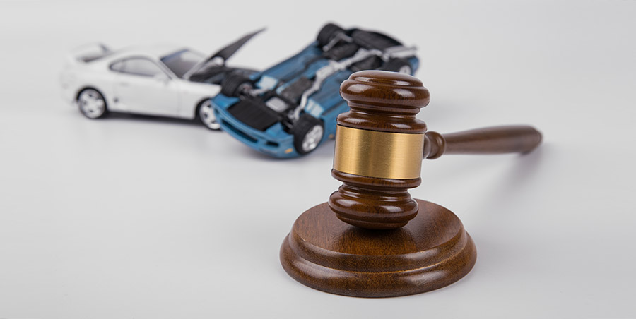 A gavel with a toy car crash in the background.