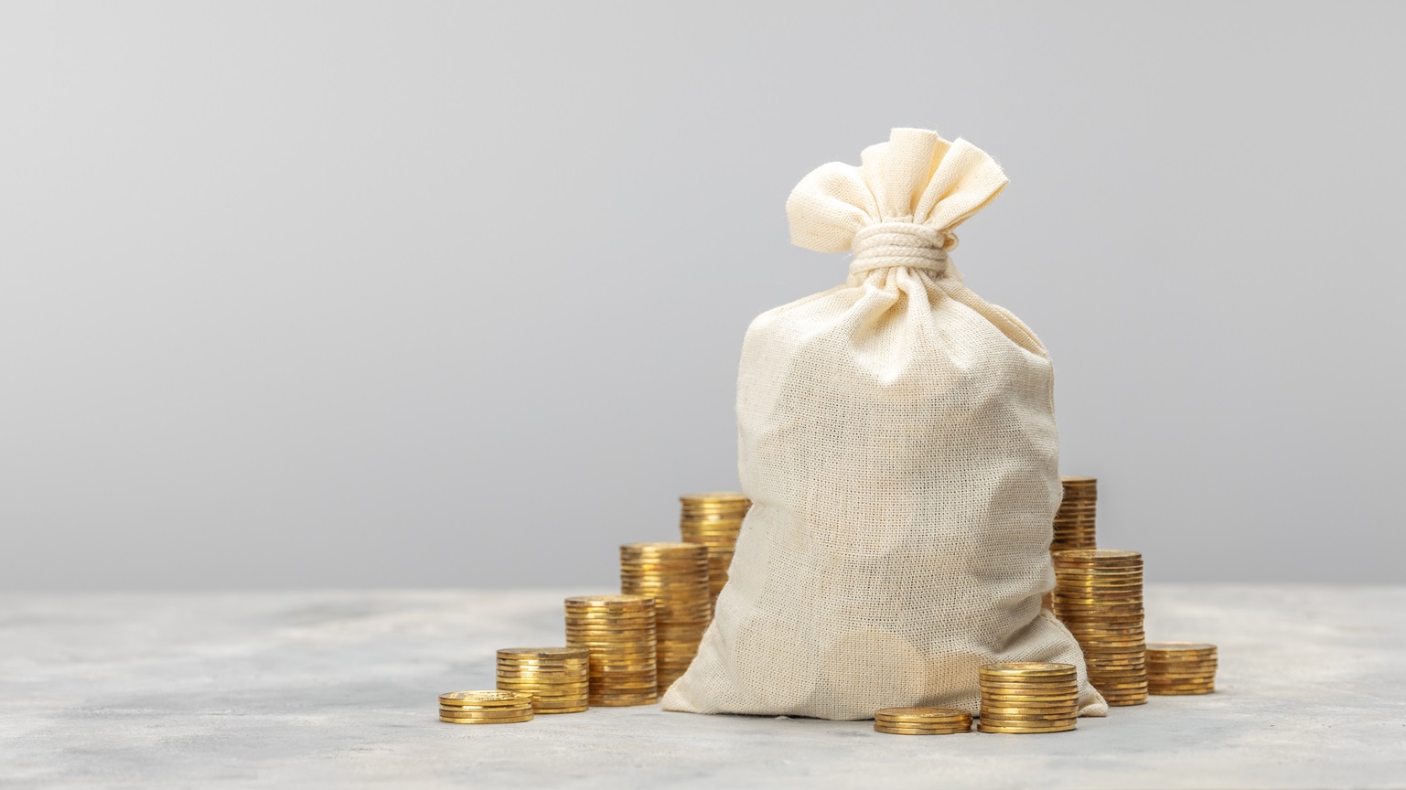A money bag with stacks of coins next to it